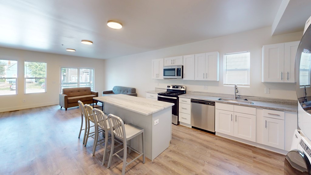 A kitchen with white cabinets and a wooden floor.